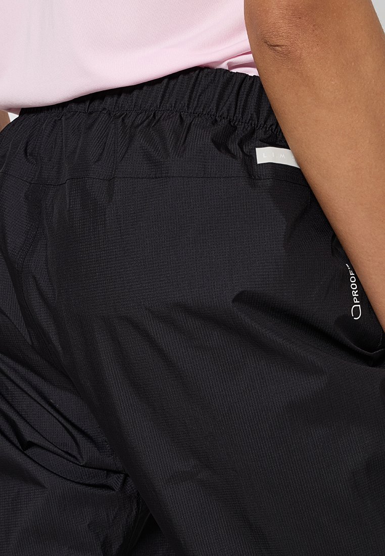 Mustat kevyet housut, joissa on teksturoitu pinta, joustava vyötärö ja logovärit. Ominaisuuksiin kuuluu rento istuvuus ja minimalistinen muotoilu.