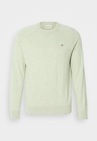 Pulover verde deschis, dintr-un material moale, cu guler rotund, mansete ribbate și un logo mic pe piept, având o croială lejeră.