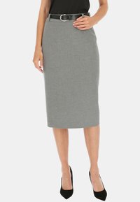 Szara spódnica ołówkowa o gładkiej teksturze, z paskiem i srebrną klamrą. Noszona z czarnymi szpilkami.