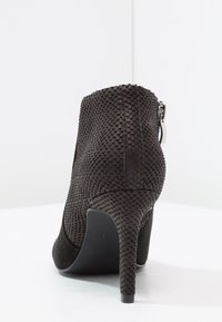 Stivaletto nero con tacco alto e sottile, realizzato in materiale testurizzato con motivo in pelle di rettile, dotato di chiusura con zip.