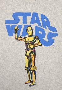 Pilkas audinys T-shirt su spalvinga C-3PO grafika iš Star Wars, virš personažo esančiu ryškiu mėlynu tekstu "STAR WARS".