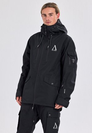 Schwarze wasserdichte Jacke mit hohem Kragen, verstellbarem Kapuzen, Fronttaschen und Logos. Glatte Textur aus strapazierfähigem Material.
