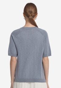 Ljusblå kortärmad tröja med rund hals och ribbad fåll. Mjuk textur med ett subtilt melerat mönster.