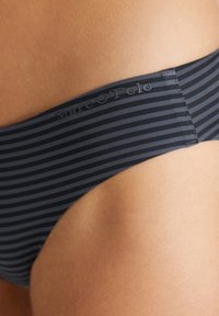 Parte inferiore di bikini a righe navy con una texture liscia, dotata di un logo sulla vita. Le cuciture piatte e una forma sagomata migliorano la vestibilità.