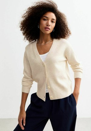 Beige cardigan with a v-neck, button front, and ribbed cuffs. Made from soft material, it features a relaxed fit and minimalistic design.