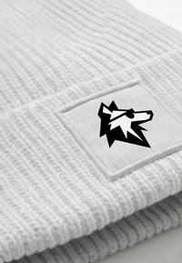 Gray ribbed knit beanie featuring a square patch with a black wolf graphic. Soft texture, folded cuff design, and monochromatic color scheme.