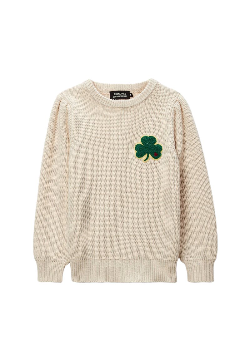 Pull en tricot couleur crème avec un col rond. Présente un patch en feutre vert en forme de trèfle sur la poitrine gauche. Manches et ourlet à côtes.