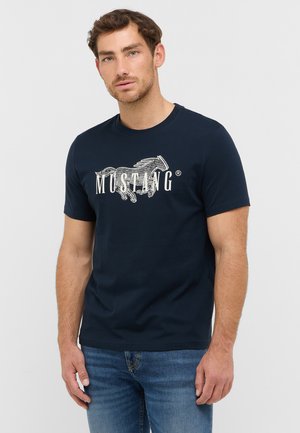 Camiseta de algodón azul marino con cuello redondo, que presenta un gráfico de un caballo galopando y la palabra "MUSTANG" en blanco. Manga corta.