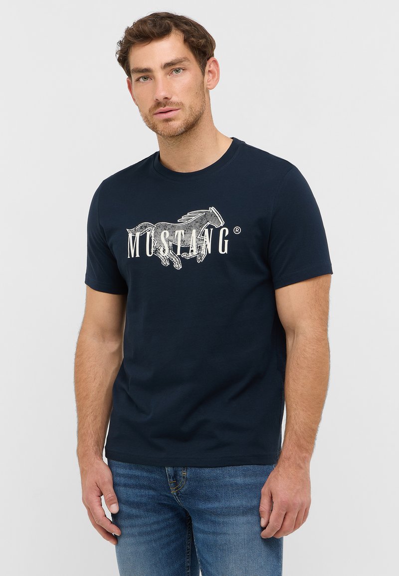 Dunkelblaues Baumwoll-T-Shirt mit rundem Ausschnitt und kurzen Ärmeln, mit einem weißen Grafikdesign eines Pferdes und dem Wort "MUSTANG" in fetter Schrift.