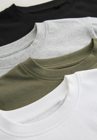 Tre magliette nei colori nero, grigio, verde oliva e bianco, con scollo rotondo e maniche corte, caratterizzate da dettagli di cuciture visibili.