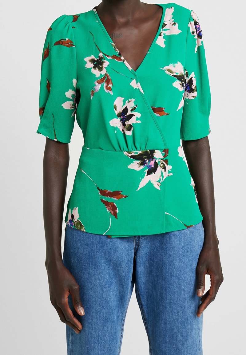 Blusa verde floral con escote en V, mangas cortas abullonadas y cintura ajustada. Fabricada con un tejido ligero de acabado texturizado.