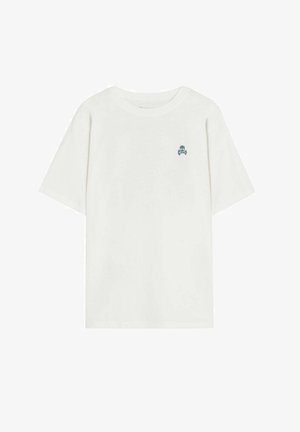 T-shirt blanc en coton à manches courtes avec un petit logo de tête de mort et os croisés sombres sur le côté gauche de la poitrine.