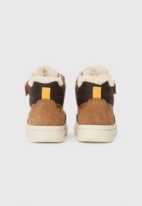 Bruna mocka och mörka tyg hightop sneakers med en fluffig foder, gula detaljer och en ljus sula.