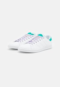 Weiße Leder-Sneaker mit lavendelfarbenen Schnürsenkeln, türkisfarbenen Akzenten an der Ferse und Zunge sowie durchbrochenen Details an den Seiten.