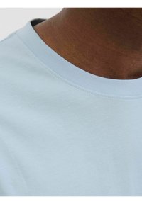 Light blue cotton t-shirt collar with ribbed texture, close-up showing smooth fabric and round neckline design.