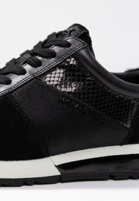 Baskets noires avec une finition en daim, panneaux en mesh, et semelle en caoutchouc. Dotées de lacets noirs et d'un logo embossé sur le côté. Design moderne.