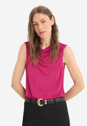 Fuchsia sleeveless top with draped neckline and soft texture, paired with high-waisted black trousers and a black belt featuring a gold buckle.