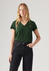 Green V-neck t-shirt made of cotton, featuring short sleeves and a small red Levi's logo. Paired with high-waisted black jeans.