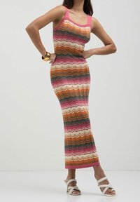 Robe en tricot avec un motif en zigzag rose, vert, orange et blanc. Sans manches, design ajusté, avec un décolleté rond et une longue bordure.