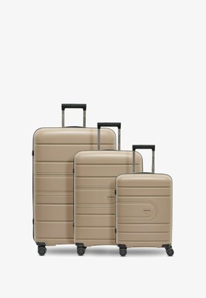 Tres maletas rígidas beige de diferentes tamaños, con cuatro ruedas y mangos telescópicos negros, dispuestas una al lado de la otra.
