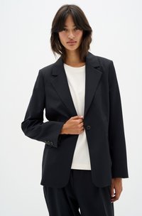 Black blazer with a structured design, single button closure, and notch lapels. The material appears smooth with a tailored fit.