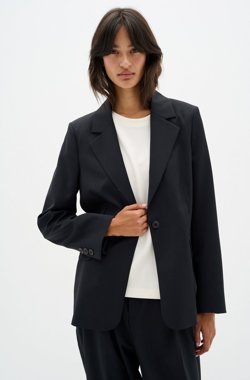 Black blazer with a structured design, single button closure, and notch lapels. The material appears smooth with a tailored fit.