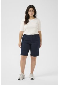 Navy bermuda shorts dengan desain yang rapi, dilengkapi dengan penutupan ritsleting dan kancing, kantong samping, dan tekstur yang halus. Dipadukan dengan atasan yang ringan.
