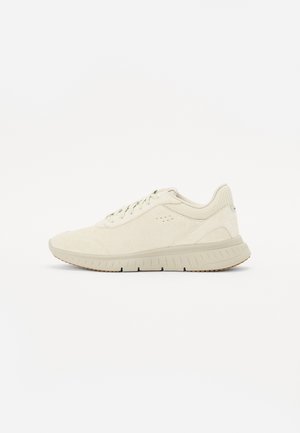 Hellbeiger Sneaker mit niedriger Schafthöhe, Schnürung vorne, gepolstertem Kragen, strukturierter Sohle und dezentem Branding an Seite und Fersenbereich.