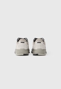 Sneakers bianchi e grigi con materiali in mesh e suede. Presentano un logo sul tallone, un colletto imbottito e accenti neri sul retro.