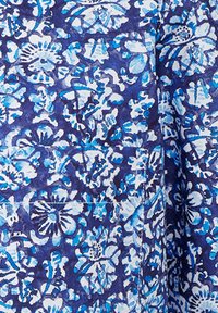 Tessuto floreale con motivi blu e bianchi su uno sfondo blu scuro; presenta una tasca; texture liscia; design intricato.