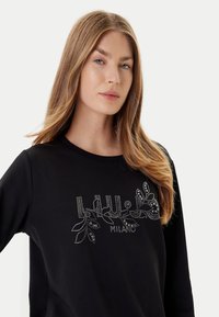 Felpa nera con scollo rotondo, maniche lunghe e decorazione floreale in strass sulla parte anteriore, con una texture liscia.