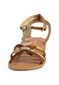 Sandalo in pelle marrone con cinturini incrociati e un accento beige testurizzato. Presenta una cinghia alla caviglia regolabile e una suola piatta con cuciture leggere.