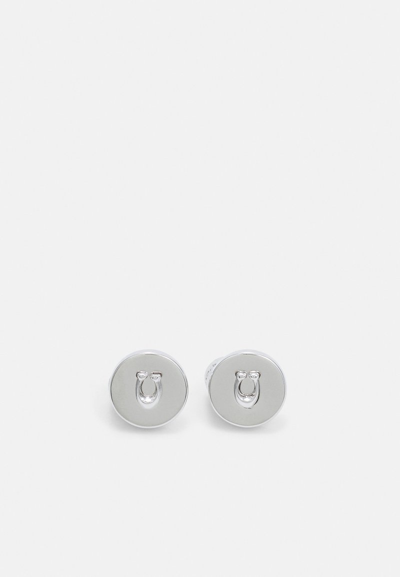 Paire de boucles d'oreilles clous rondes en argent, chacune avec un design en relief de fer à cheval au centre sur fond blanc uni.