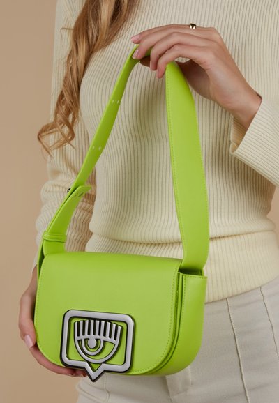 Sac bandoulière en simili cuir vert avec une forme arrondie, une quincaillerie argentée en forme d'œil et une large sangle réglable.