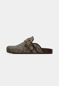 Træsko med en lysebrun lærredsoverside med et gentaget mønster og en mørkebrun gummisål. Fremhævet med en guldfarvet spænde.