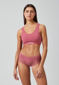 Roze katoenen bh met een brede band met witte tekst. Bijpassende roze onderbroek met kant en een semi-transparant ontwerp. Soepele textuur.