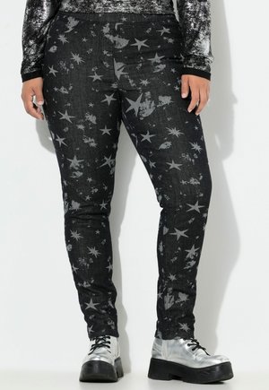 Sorte slim-fit bukser med grå stjerne- og flekkemønstre båret med sølv platform-sko og en langærmet tekstureret top.