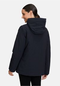 Veste bleu marine avec capuche, en tissu doux et texturé, à la coupe décontractée, vue de dos avec un minimum de détails.