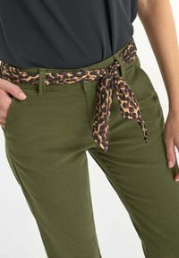 Olijfgroene broek met een gestrikte luipaardprint riem. De stof lijkt glad en heeft een slim fit ontwerp met zijzakken.