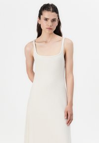Ribbet midi-kjole i lys beige, med firkantet utringning og tynne stropper, med en tettsittende liv og et flytende skjørt.