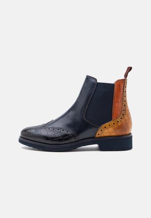 Bottine Chelsea en cuir avec bout et talon brogue noirs, détail en cuir texturé marron, panneau latéral élastique et languette à l’arrière.