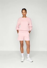Sweatshirt rose pâle et shorts assortis en tissu doux, dotés d'un col rond et d'une coupe décontractée, avec des poignets et une taille côtelés.