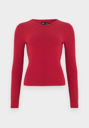 Top rouge à manches longues côtelé avec un col arrondi. Confectionné dans un tissu doux, silhouette ajustée et détails subtils de texture. Étiquette de la marque visible.