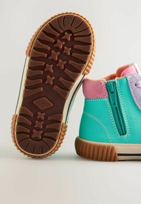 Kolorowe dziecięce buty z turkusową skórzaną cholewką, różowymi zamszowymi akcentami, bocznym zamkiem błyskawicznym oraz fakturowaną brązową gumową podeszwą z wzorem gwiazdek.