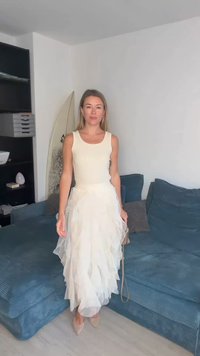 Hvid ærmeløs top kombineret med en hvid lagdelt nederdel med en let og luftig tekstur. Beige spidse sko og en lille håndtaske medfølger.