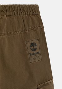 Timberland bruine cargoshorts van een geweven textuurstof, met een elastische tailleband en een logo patch aan de zijkant.