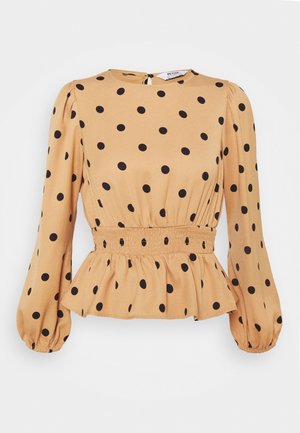 Beige blouse met lange mouwen en zwarte stippen, verzamelde elastische tailleband, peplumzoom en knoopsluiting in de nek aan de achterkant.