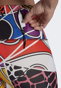 Leggings de sport colorés présentant un mélange de motifs géométriques et animaux. Comprend une poche zippée à l'arrière de la taille pour le stockage.