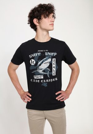 Sort bomulds t-shirt med et stort grafik af en haj, "Sharky & Co." tekst og tal på fronten. Korte ærmer og rund halsudskæring.