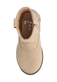 Botín de ante beige hasta el tobillo con suela marrón, cremallera lateral y costuras decorativas que parecen patrones florales en la parte superior.